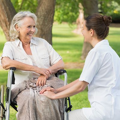Eine alte Dame im Rollstuhl führt ein Gespräch mit einer Pflegekraft