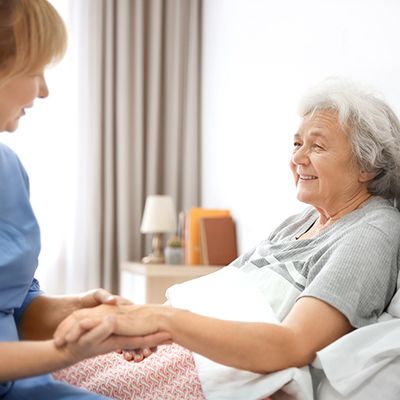 Eine Pflegekraft hält die Hand einer älteren Frau und bietet ihr Trost und Unterstützung