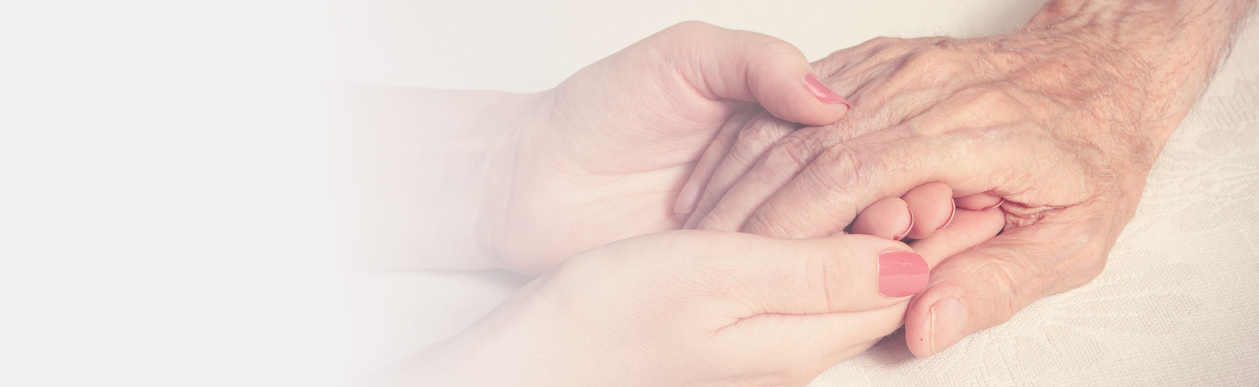 Eine ältere Frau und eine junge Frau halten Händchen, was eine herzliche Beziehung zwischen den Generationen symbolisiert